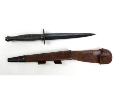 A Fairbairn-Sykes type fighting knife with blackened blade to ribbed grip, length 29.5cm, in leather scabbard.Additional Info