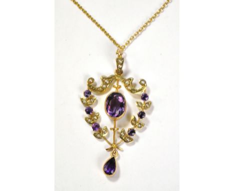 An Edwardian 9ct yellow gold open frame shield shaped pendant centred with an oval cut amethyst flanked by six smaller stones