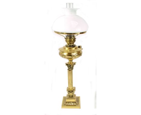 A brass Corinthian column oil lamp on stepped square base with ribbon decorated brass reservoir and opaque glass shade raised