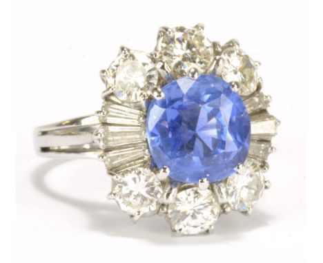 A white metal diamond and sapphire ring, the oval sapphire of good cornflower blue colour, approx 2.5cts, within a border of 