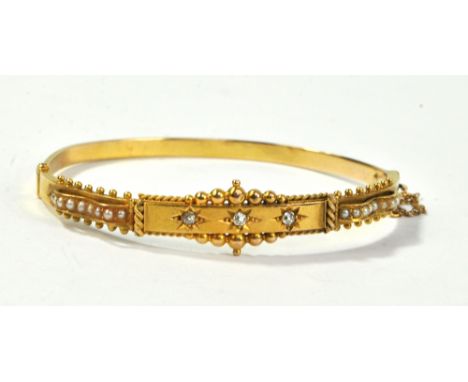 A circa 1900 yellow metal snap bangle set with a round cut diamond to the central section, weighing approx 0.03ct, flanked by