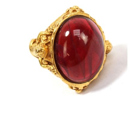 ELIZABETH TAYLOR FOR AVON; a large vintage gilt signet ring with oval cranberry coloured cabochon flanked by shanks modelled 