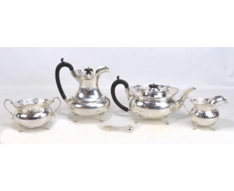 H QUIBELL &amp; SON; a George V hallmarked silver four piece tea set comprising an oval teapot with raised pierced rim, on fo