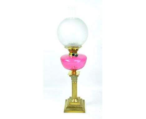 A late Victorian brass oil lamp with cranberry wrythen moulded reservoir, short Corinthian column base and etched globular gl