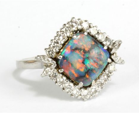 An 18ct white gold opal and diamond ring, the cushion shaped opal measuring 10 x 10mm, diagonally set within a border of eigh