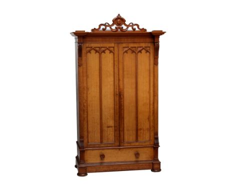A large light oak Gothic revival wardrobe with pierced pediment above arched Gothic detailed doors enclosing slides and drawe