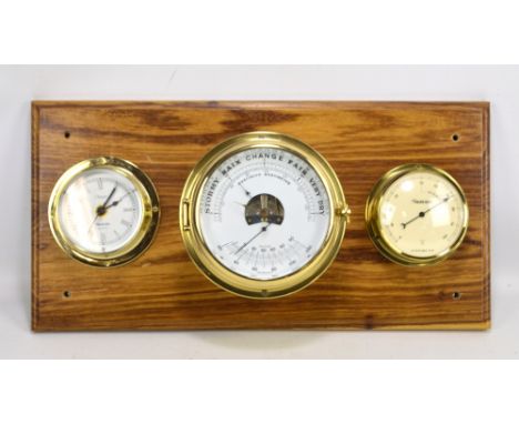 A brass cased ship's style barometer, hygrometer and clock three piece set mounted on wooden board, two stamped for Nauticali
