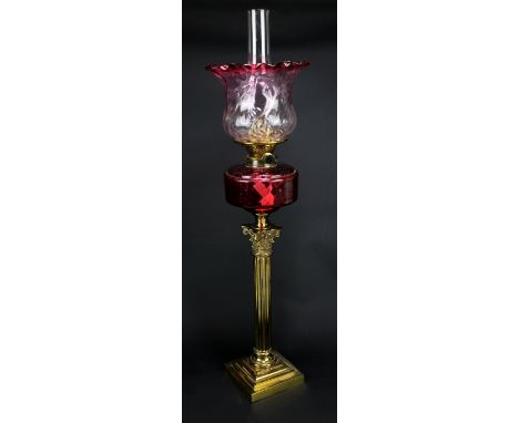 A brass Corinthian column oil lamp on stepped square base with cranberry glass reservoir and shade with crimped rim, duplex b