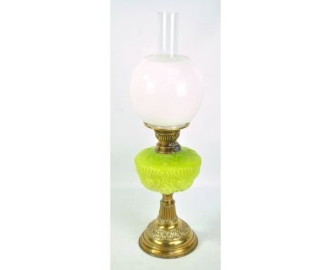 A brass oil lamp with green glass reservoir, opaque white shade and associated clear glass chimney, inscribed above reservoir