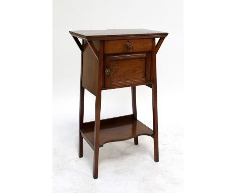 An Edwardian Arts and Crafts walnut side table with single drawer above cupboard door raised on square supports united by an 