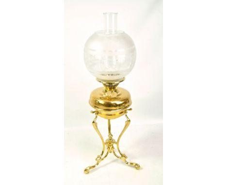 A brass oil lamp on tripartite stand with brass reservoir, etched globular glass shade and clear chimney, height 65cm.