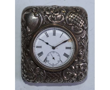 An Edwardian silver rounded rectangular easel dressing table timepiece, 4cm enamel clock dial, the case profusely chased with