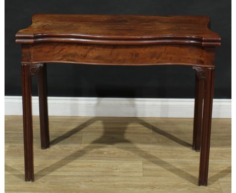 A George III mahogany serpentine card table, hinged top enclosing a baize lined playing surface, above a deep frieze, moulded