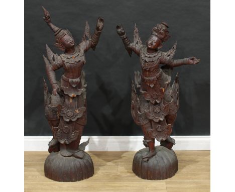 A pair of large Thai carved figures of dancers, each standing in traditional dress, lobed oval bases, 118cm and 108cm high 