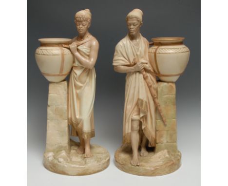 A pair of Worcester figures, Nubians, modelled by James Hadley, both standing in Eastern dress holding oversize amphorae, in 