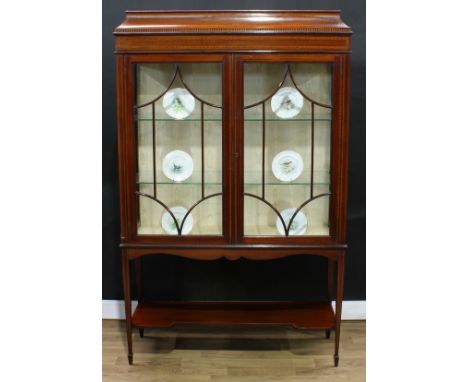 An Edwardian mahogany display cabinet, rectangular concave-moulded caddy top with faux-dentil band above a pair of astragal g