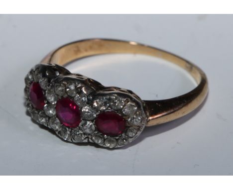 An Edwardian ruby and diamond cluster ring, tree panel cluster inset with three mid tone pinky red rubies, each approx 0.30ct