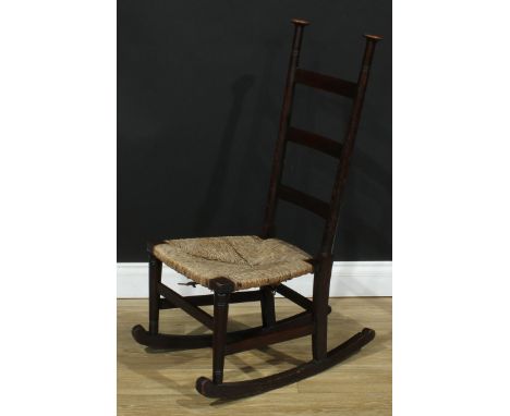 An Arts &amp; Crafts oak ladder back rocking chair, in the manner of Liberty &amp; Co, each stile crested by a mushroom-form 