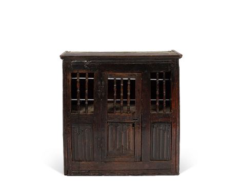 A James I oak food hutch, with moulded cornice and a hinged door with turned grilled top and linen fold panel base, flanked b