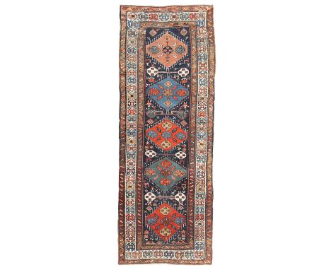 A South Caucasian runner Karabagh region, circa 1920, the indigo field of five polychrome hooked lozenge medallions, the fiel