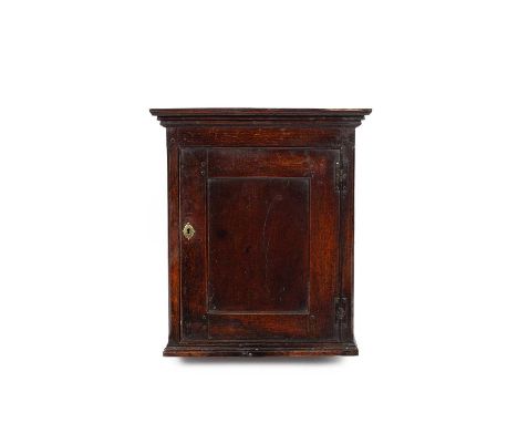 A George II oak hanging cupboard, the panel door enclosing two fitted ogee shaped shelves, 64.5cm wide, 25cm deep, 73.5cm hig