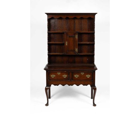 An 18th Century style oak dresser, the raised back with cupboard door, above two drawers on cabriole supports, 107cm wide, 45