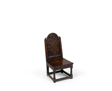 A James I carved oak low chair, the back profusely carved with foliage and lunettes and with an arched lunette crest above a 