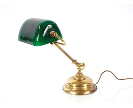 A brass adjustable desk lamp, having green glass shade