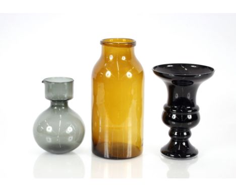 An amber glass cylindrical jar, 30cm high; a black glass bell shaped vase; and a smoked glass pitcher