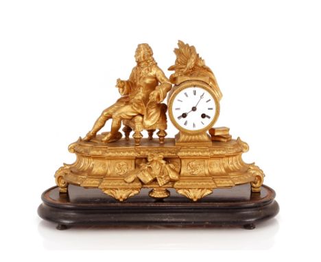 A 19th Century French gilded mantel clock decorated with a figure of a reclining scholar and foliage, 8 day movement striking