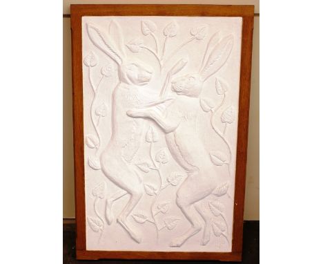 A decorative white plaster wall plaque, depicting boxing hares amongst foliage contained in a moulded light wood frame, 93cm 