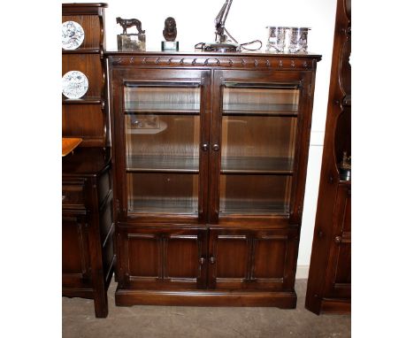 A dark Ercol glazed display cabinet, fitted interior shelves and cupboards below, 101cm wide x 138cm high x 32cm deep