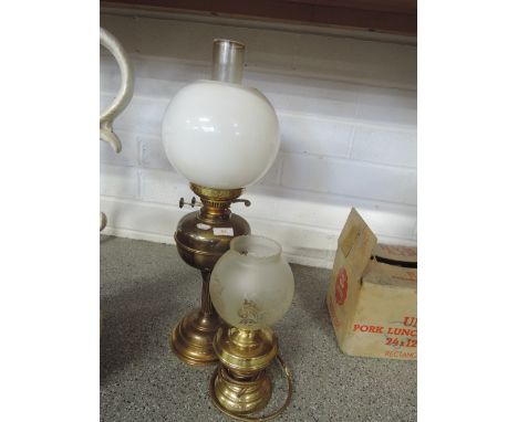 A brass oil lamp with shade and chimney and similar electric lamp