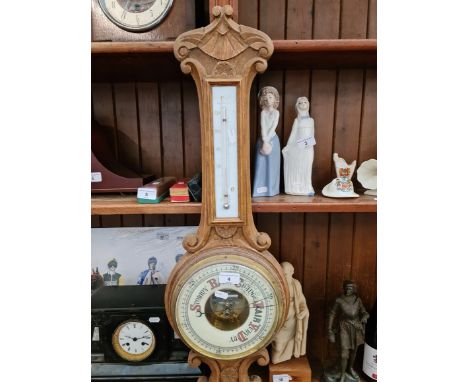A wooden cased barometer with enamelled face.Dimensions:- 82cm height, 20cm diameter dial, thermometer panel height 24cm & 4.