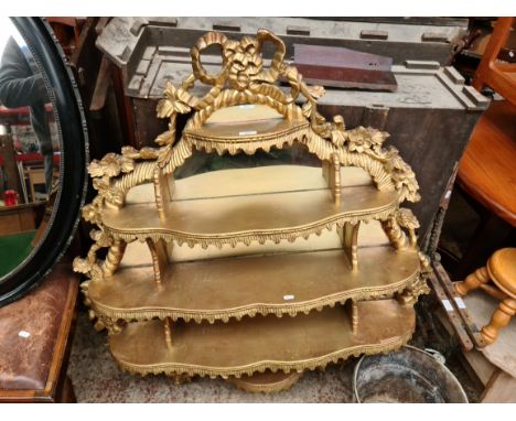 A large baroque style ornate gilded mirror with shelves. 