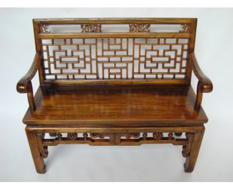 A late 19th/early 20th Century Chinese elm bench with geometric fretwork back, open scroll arms and solid seat, raised square