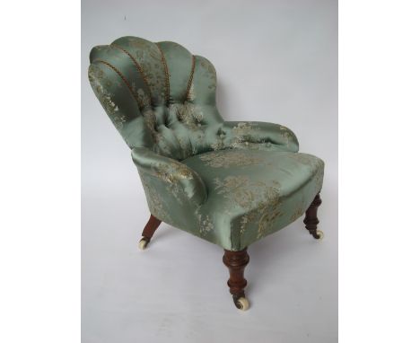 A Victorian buttonback upholstered walnut nursing chair, with shell shaped back, raised on turned forelegs and ceramic caster