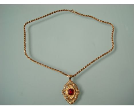 A 15 carat gold ruby set pendant, the raised oval stone within foliate scroll surround on 18 carat gold twisted rope chain, a