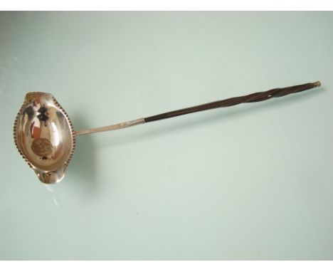 An 18th Century white metal double lipped punch ladle, the bowl with crimped rim inset with a coin, on a white metal tipped t