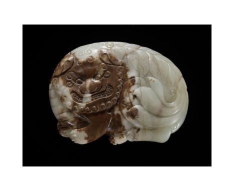 A PALE CELADON AND BROWN JADE 'BUDDHIST LION' BELT BUCKLE, MING DYNASTYChina, 1368-1644. Finely carved as a coiled Buddhist l