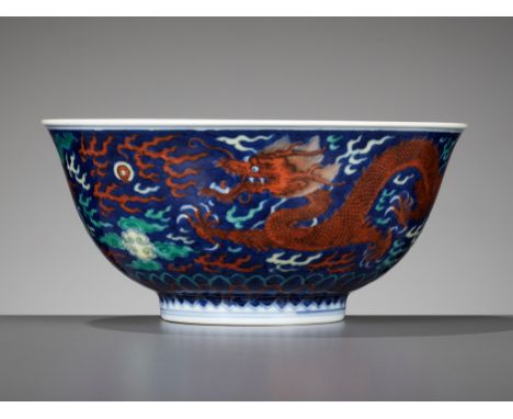 A RARE BLUE-GROUND POLYCHROME-DECORATED 'DRAGON' BOWL, QIANLONG MARK AND PERIODChina, 1736-1795. Superbly potted with deep ro