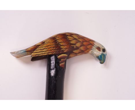 A wooden walking stick with carved and painted eagle handle
