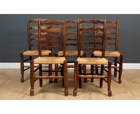 A matched set of twelve antique and later ladder back kitchen chairs with rush seats and turned supports, to include two carv
