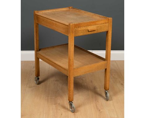 An early to mid 20th century Heal's light oak tea trolley with a single drawer, undertier and casters, having a Heal's Totten