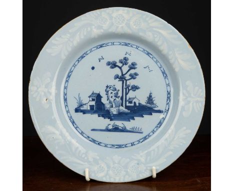 An 18th century English bianco sopra bianco delftware plate, the blue ground with central blue Oriental style rural scene, 23