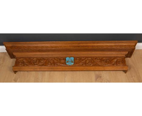 An architectural carved oak overdoor crest, with central blue and gilt shield flanked by scrolling floral and foliate decorat