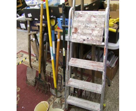A group of vintage and modern garden tools: forks, rakes, spade, lawn rake, step ladders etc.