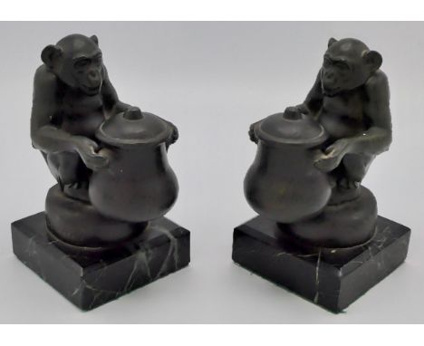 Max Le Verrier (1891-1973) - a pair of bronze bookends modelled as seated chimpanzees each holding a lidded urn inkwell, sign