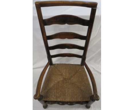 Early 19th century oak framed nursing chair, ladder back with scrolled arms and rush seat, on tapering cylindrical front legs