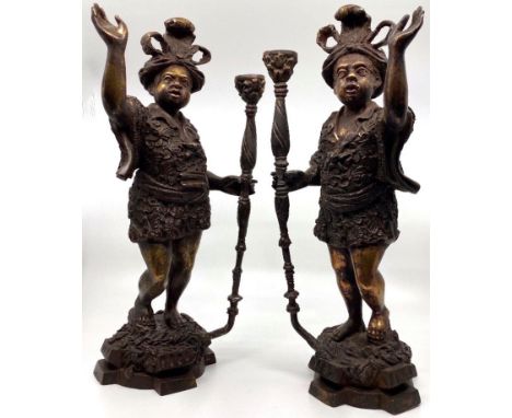 Pair of bronze Blackamoor candle holders, each modelled as a robed man holding a lamp staff and the other arm aloft, on four-